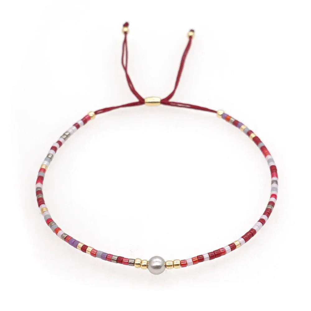 Close-up of a colourful handmade Bohemian bracelet with a lucky stone bead and geometric glass beads on a wrist.