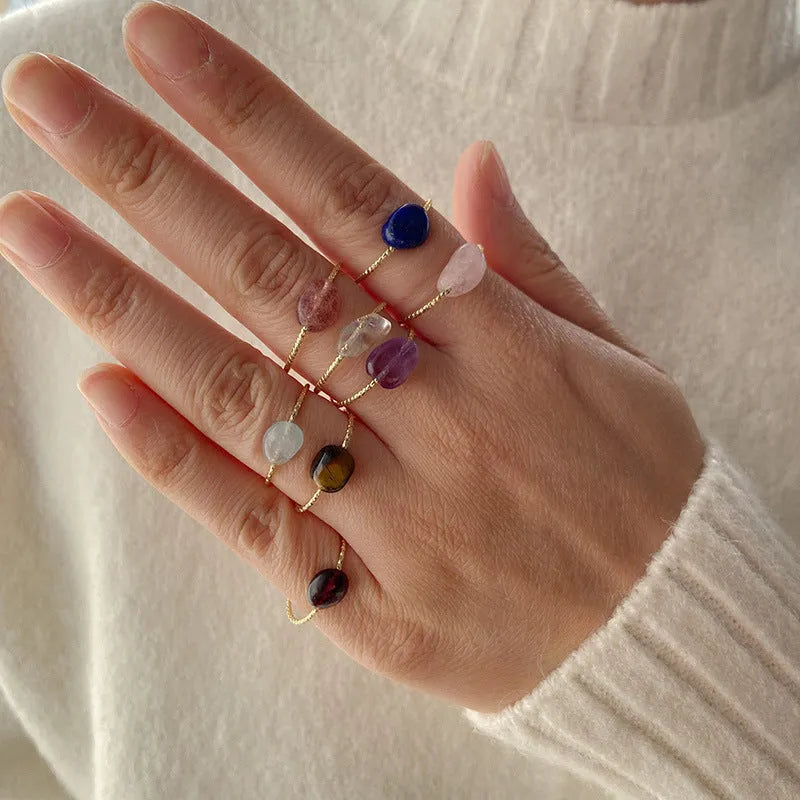 A geometric silver-toned ring setting holding a polished oval agate stone in a blue-green colour.
