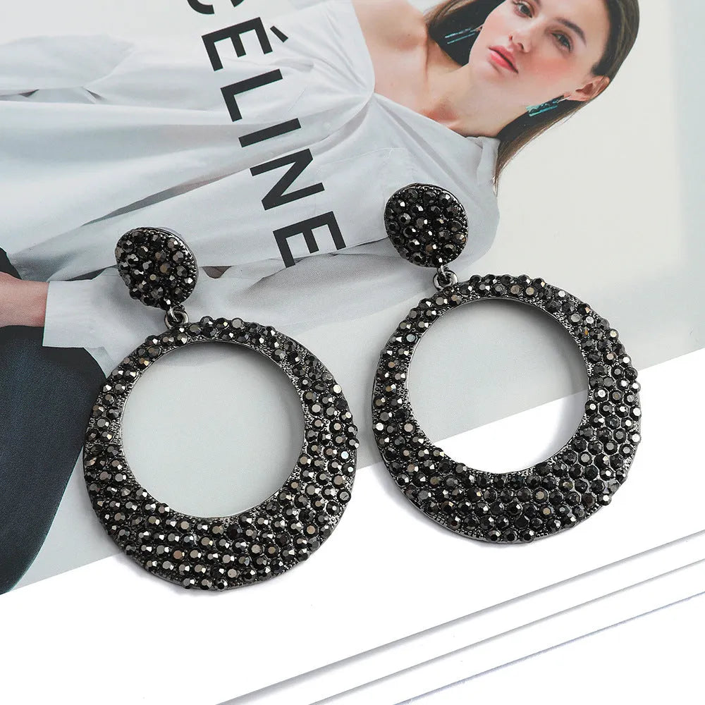 A pair of colourful metal alloy drop earrings with a large round pendant and diamond accents.