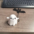 Miniature resin statue of a walking ghost dog holding a bat, a Halloween decoration.