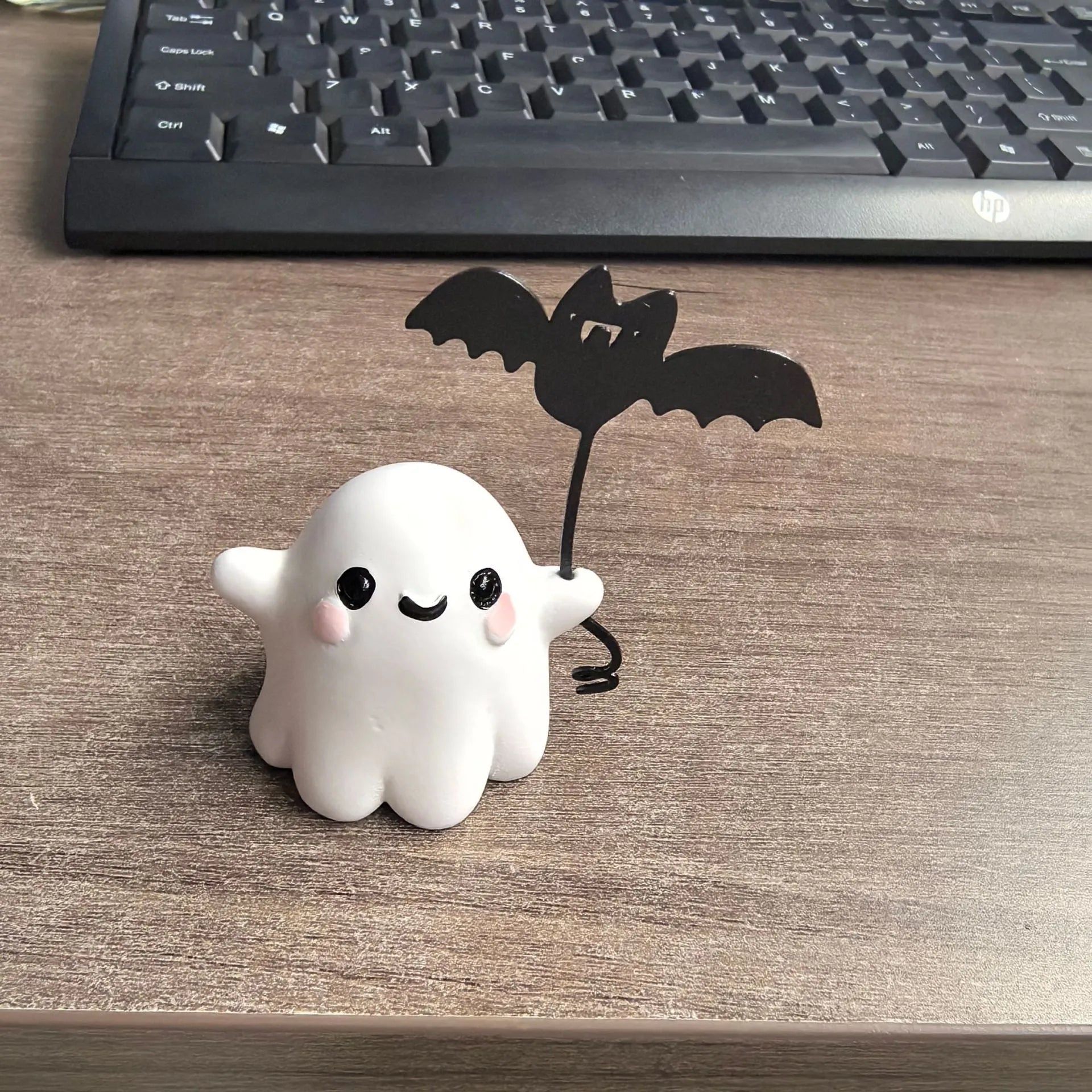 Miniature resin statue of a walking ghost dog holding a bat, a Halloween decoration.
