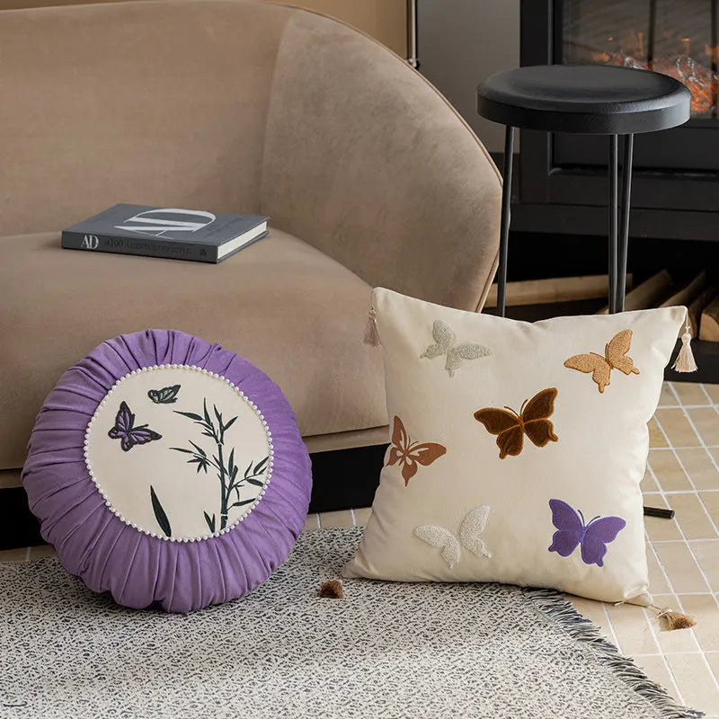 Square beige, black, and purple cushion with Chinese style embroidered butterfly pattern.