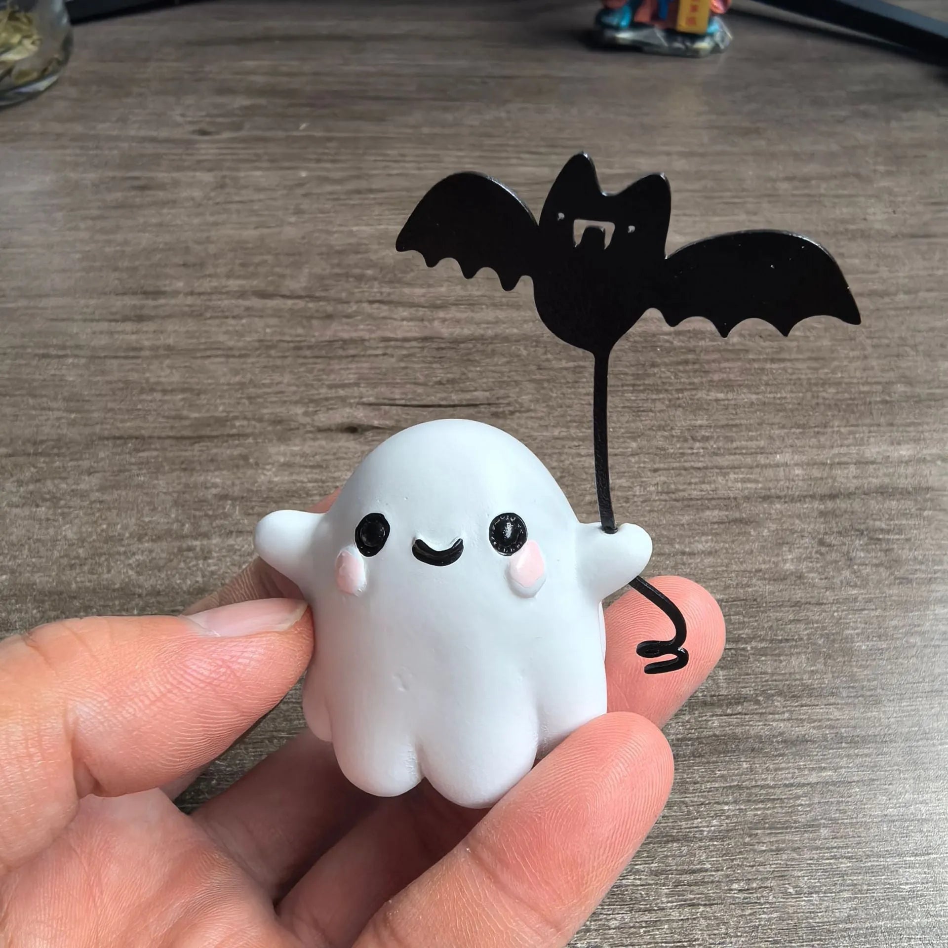 Miniature resin statue of a walking ghost dog holding a bat, a Halloween decoration.