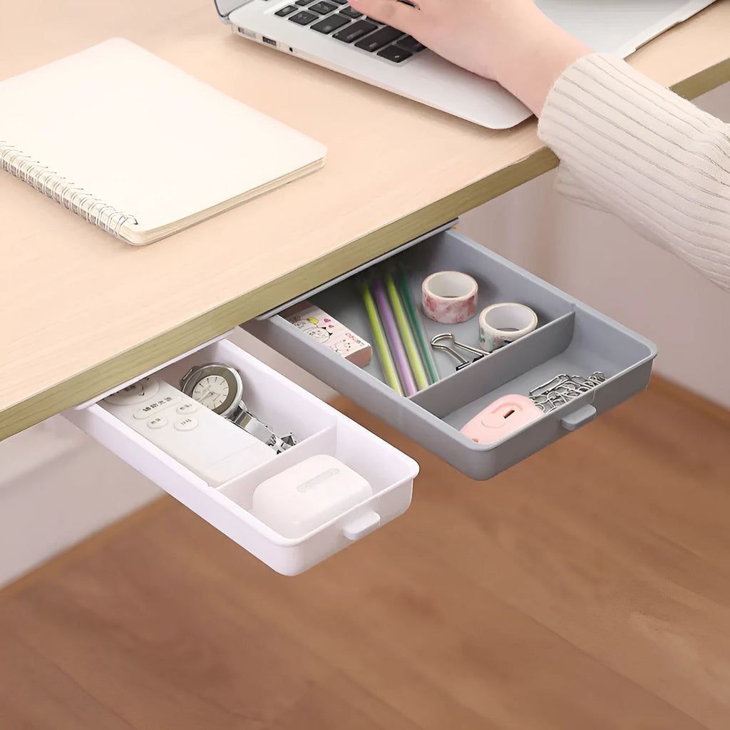 Small white plastic storage drawer with a cover and internal grid, shown placed under a wooden table.
