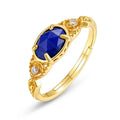 Close-up of a silver alloy ring with an elliptical geometric shape and a central natural lapis lazuli stone.