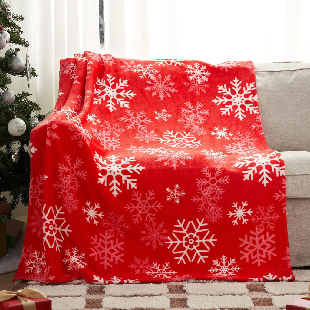 Soft red plush Christmas blanket draped over a sofa, showing its textured flannel material.