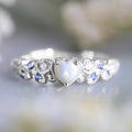 White electroplated alloy women's ring in a peach heart shape with flower and opal ocean design details.