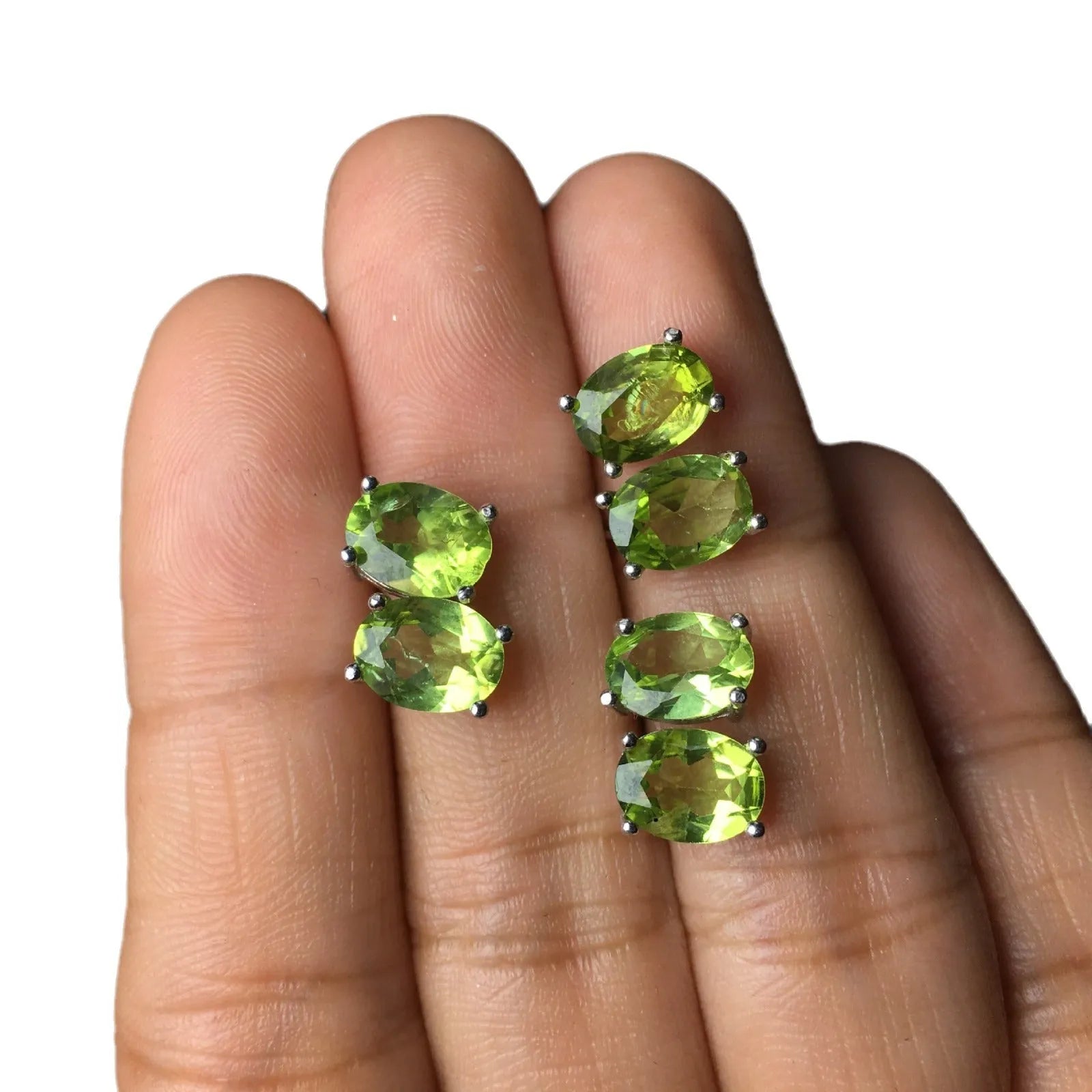 Close-up of grass green olivine stud earrings in sterling silver, showing elliptical faceted stone.