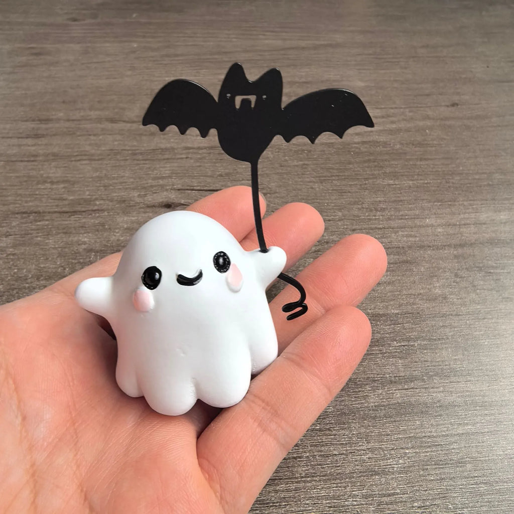 Miniature resin statue of a walking ghost dog holding a bat, a Halloween decoration.