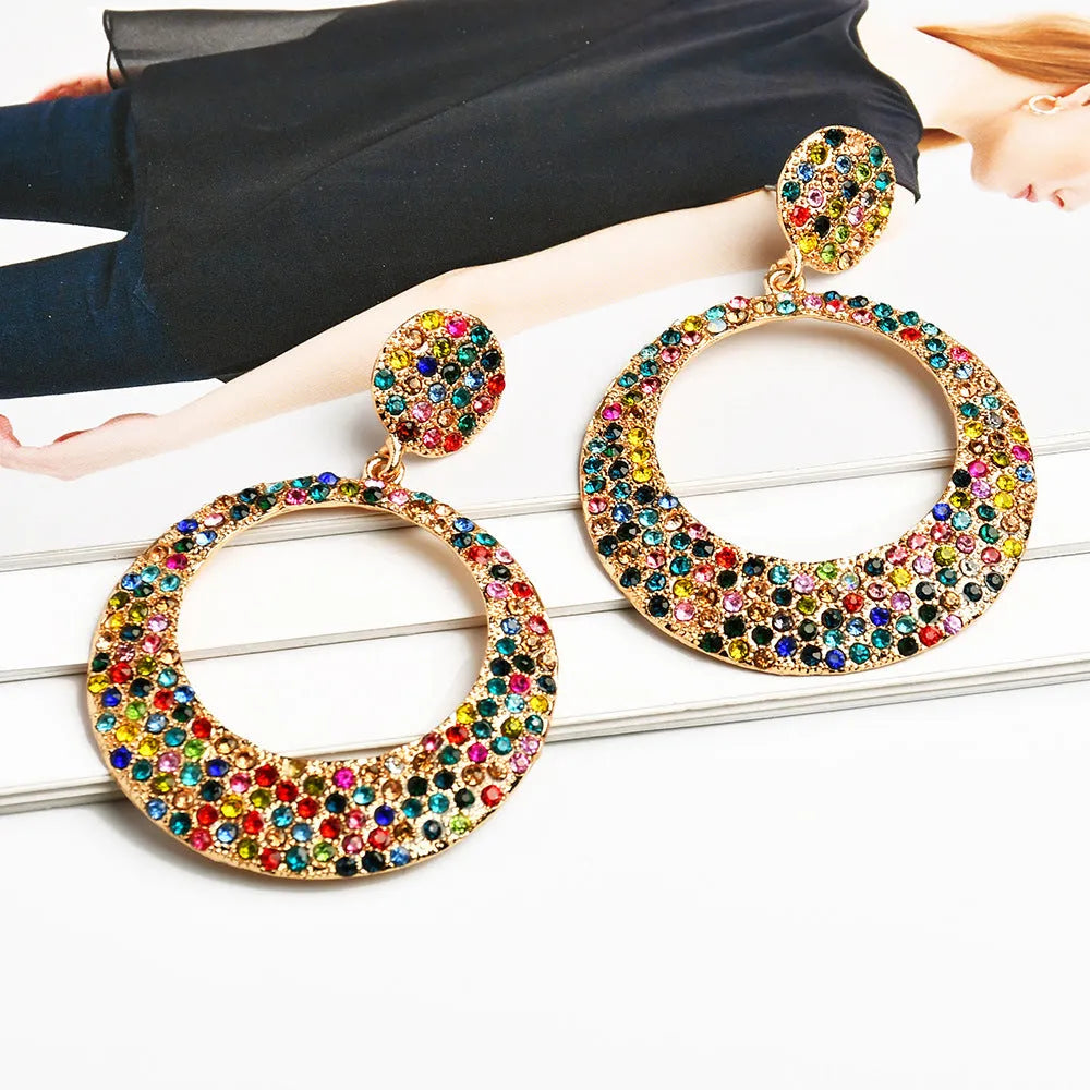 A pair of colourful metal alloy drop earrings with a large round pendant and diamond accents.