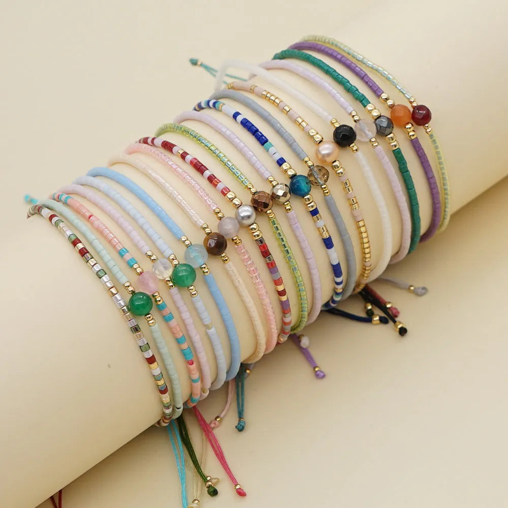 Close-up of a colourful handmade Bohemian bracelet with a lucky stone bead and geometric glass beads on a wrist.
