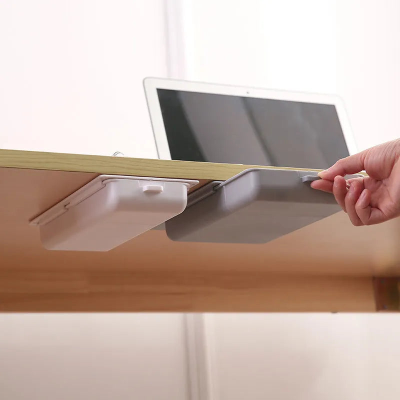 Small white plastic storage drawer with a cover and internal grid, shown placed under a wooden table.