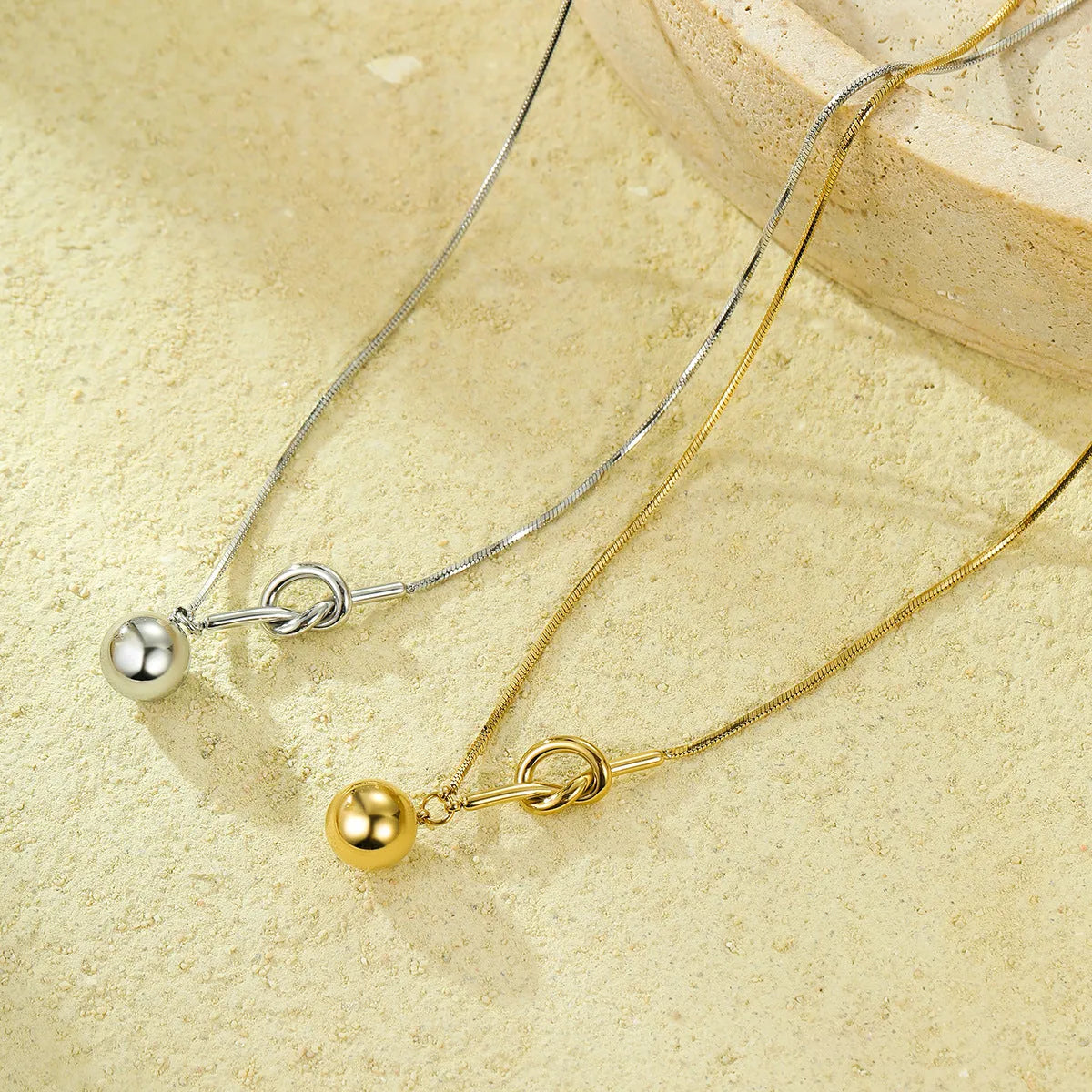 18K gold plated stainless steel winding ball pendant necklace for women on a white background