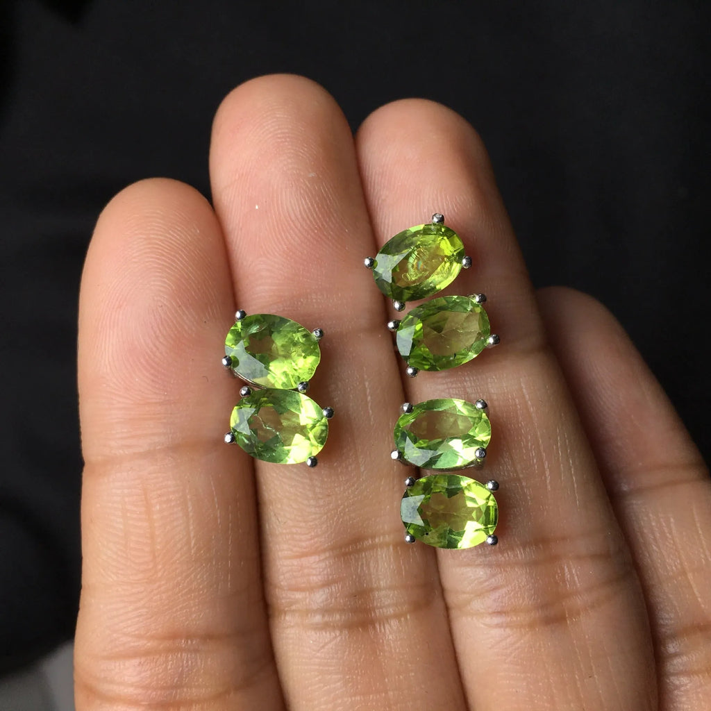 Close-up of grass green olivine stud earrings in sterling silver, showing elliptical faceted stone.