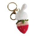 White hand-woven rabbit and strawberry wire pendant with an attached key.