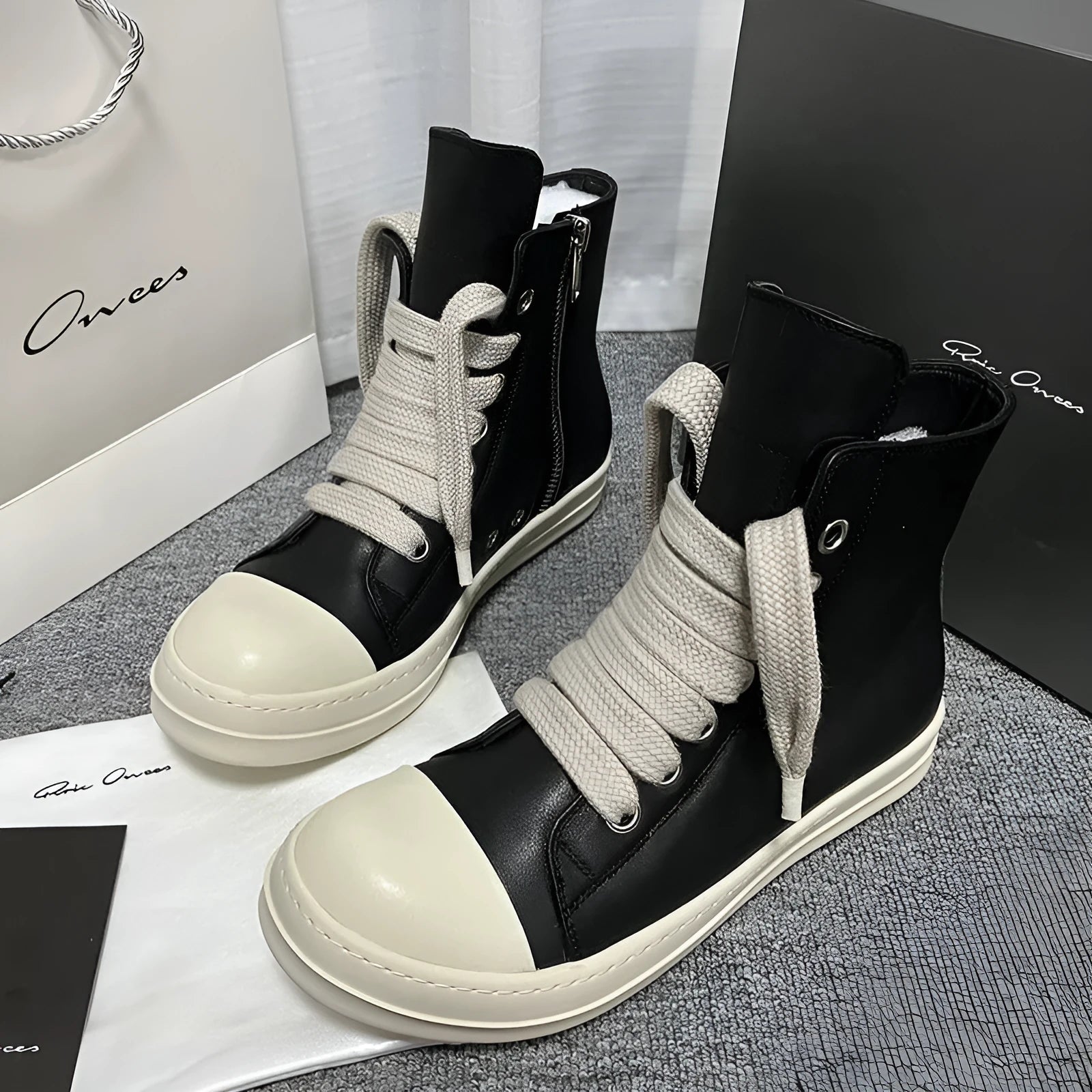 Black high-top leather sneakers with side zipper and round toe on a rubber sole.