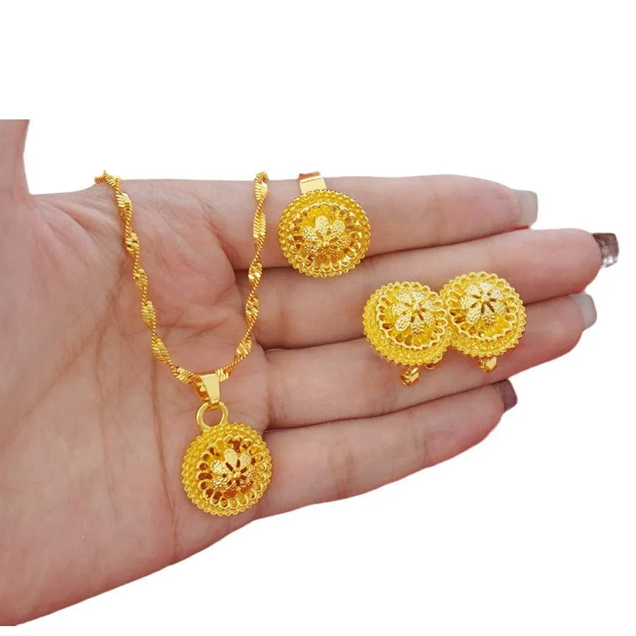 Gold-plated jewellery three-piece set with flower design pendant, matching earrings, and ring on display