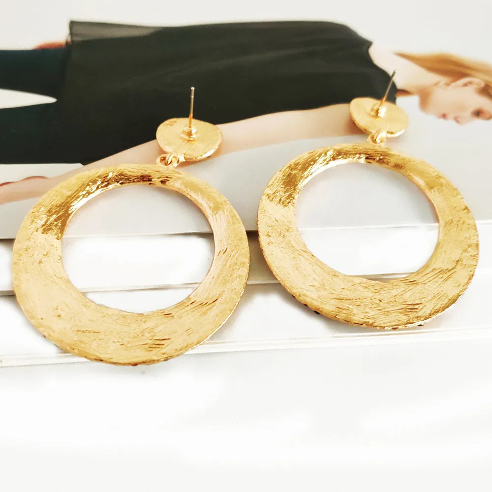 A pair of colourful metal alloy drop earrings with a large round pendant and diamond accents.