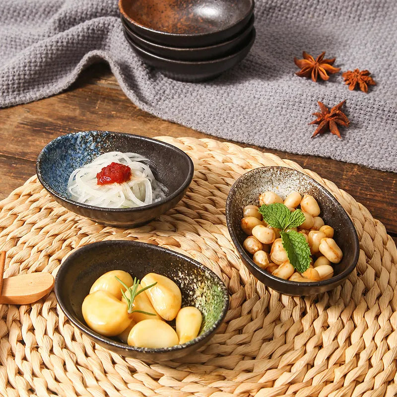 Oval Japanese ceramic dipping sauce bowl with Edo Pattern design on a dark surface.
