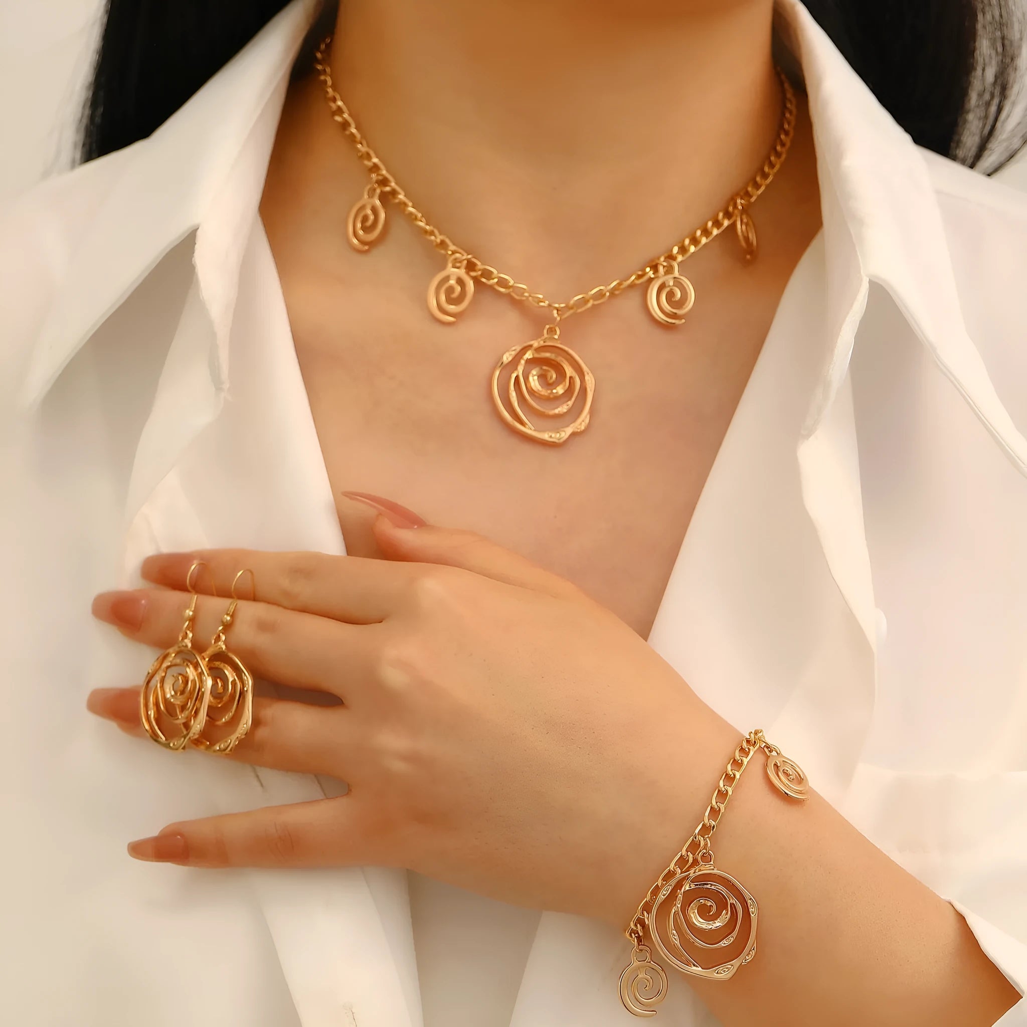 Gold spiral donut charm jewellery set showing necklace, bracelet and earrings on a white background