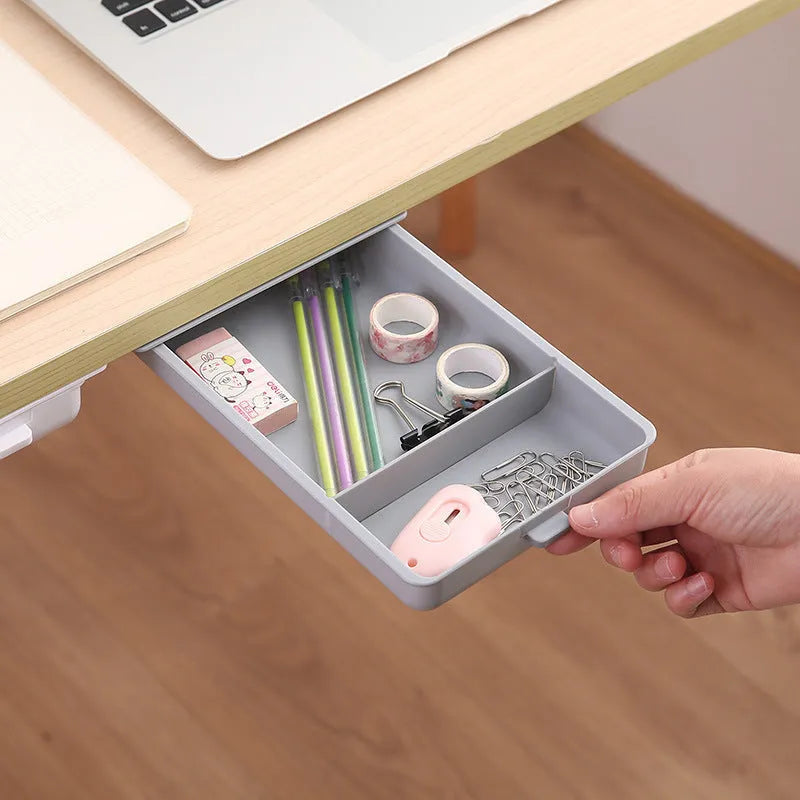 Small white plastic storage drawer with a cover and internal grid, shown placed under a wooden table.