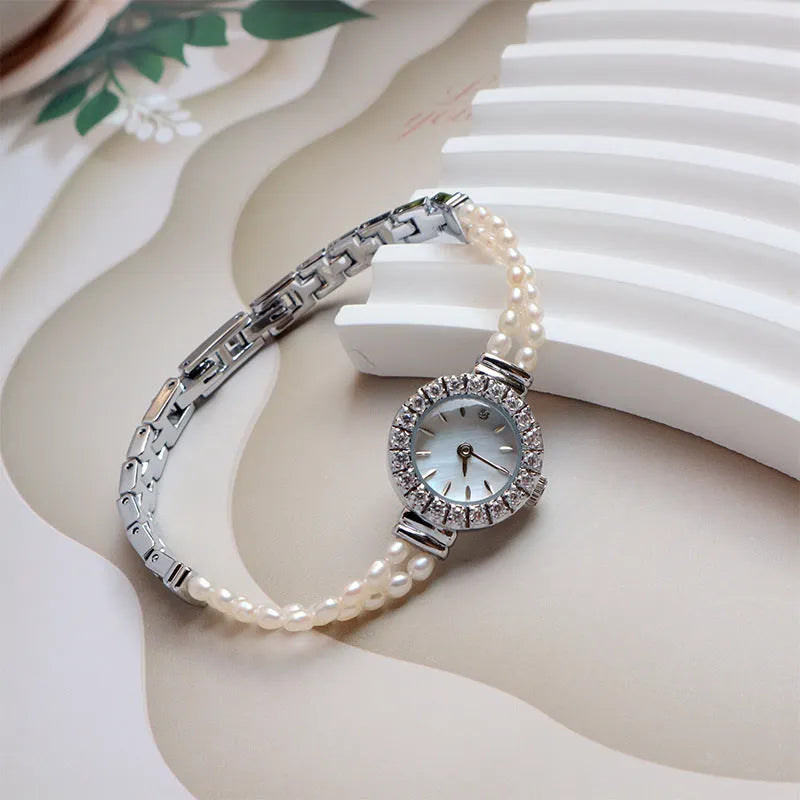 Light gold women's watch with a stainless steel strap featuring integrated freshwater pearls and a round white dial.