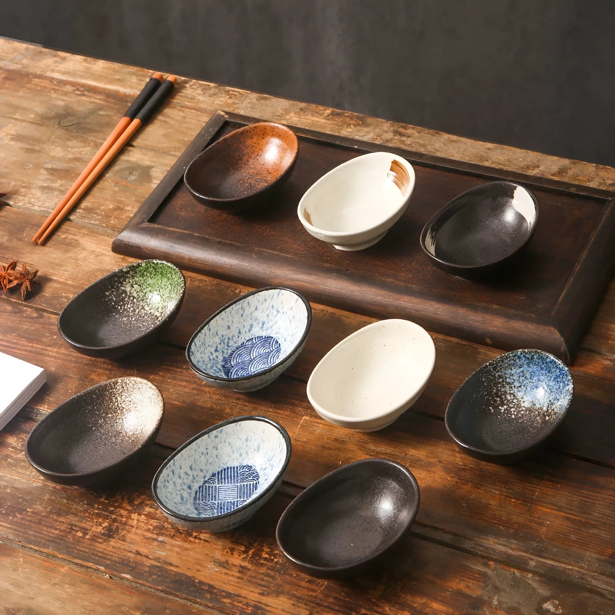 Oval Japanese ceramic dipping sauce bowl with Edo Pattern design on a dark surface.