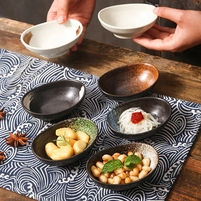 Oval Japanese ceramic dipping sauce bowl with Edo Pattern design on a dark surface.