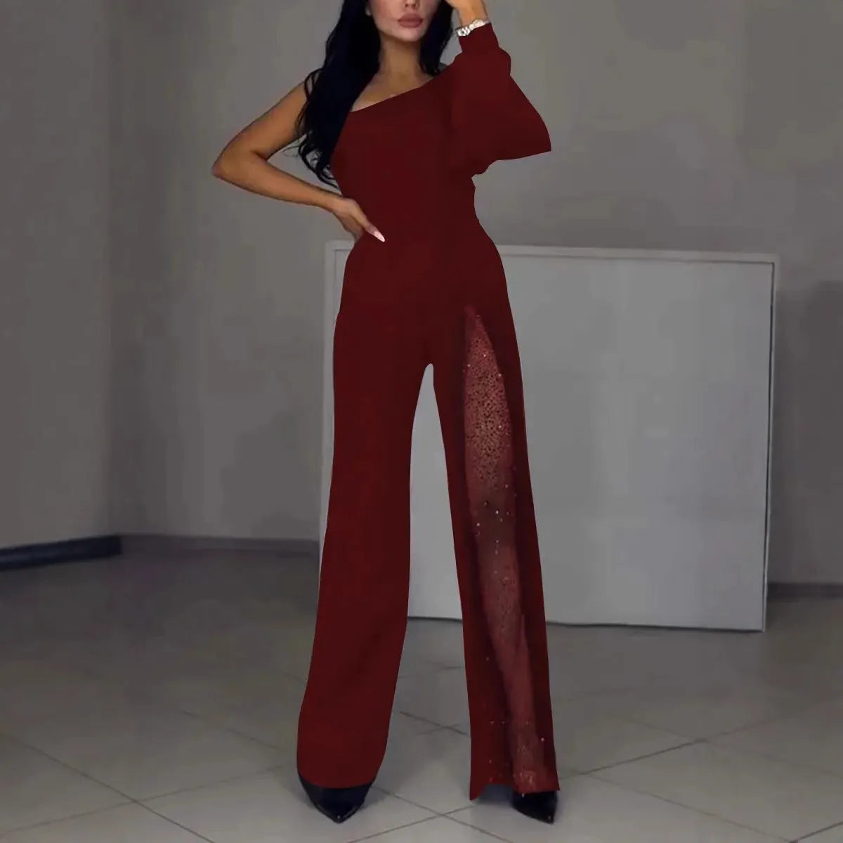 Women's black polyester jumpsuit with an oblique shoulder and a high slit on the leg, featuring long sleeves.