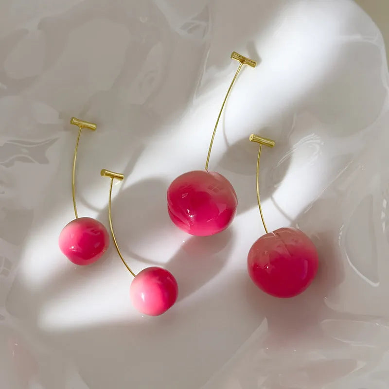 A pair of acrylic peach fruit earrings on a copper post, showing small and large size options.
