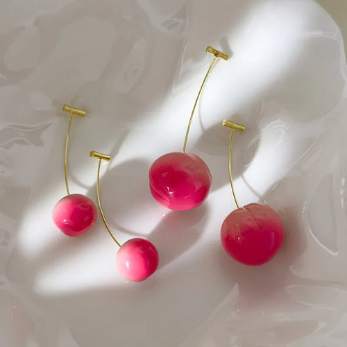 A pair of acrylic peach fruit earrings on a copper post, showing small and large size options.