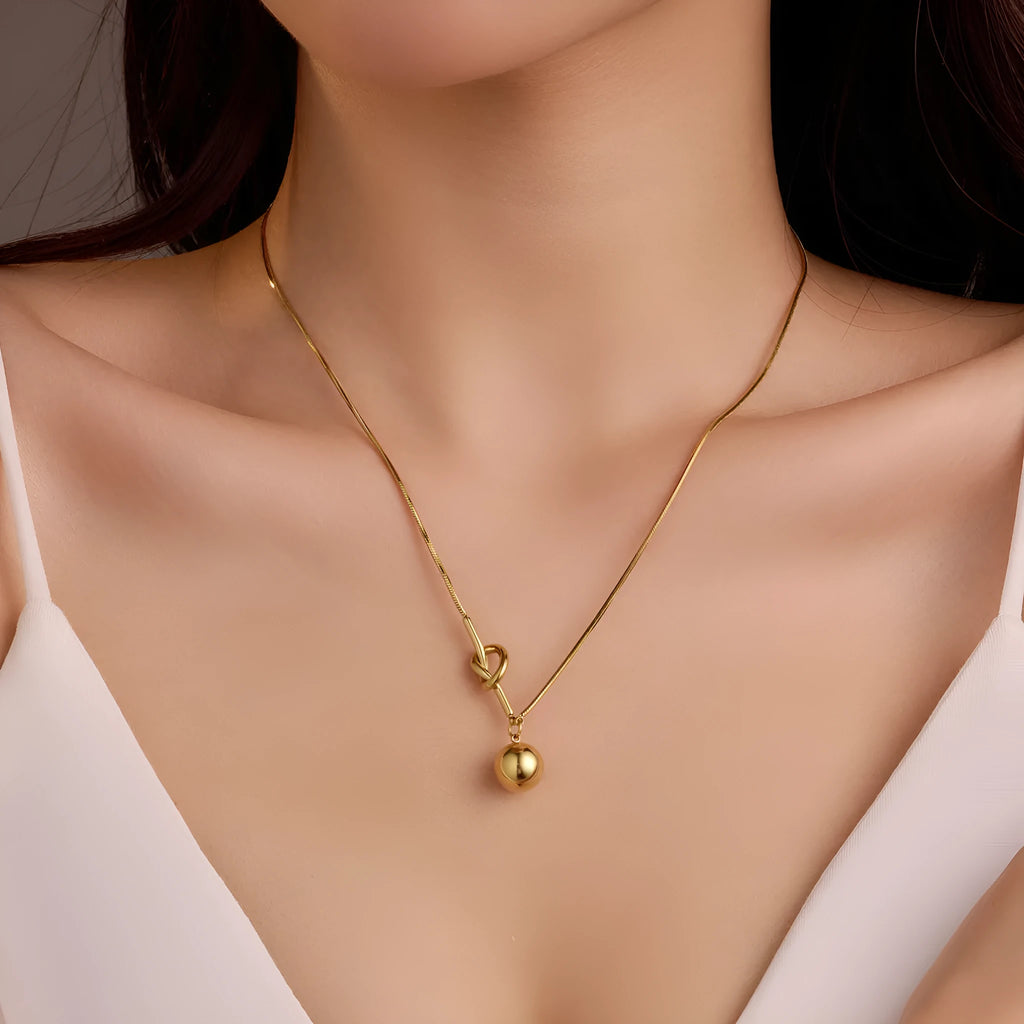 18K gold plated stainless steel winding ball pendant necklace for women on a white background