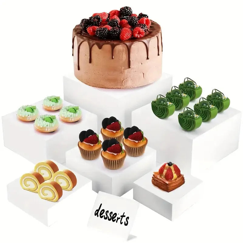 Six white modular plastic cube units arranged as a tiered dessert display stand holding cupcakes.