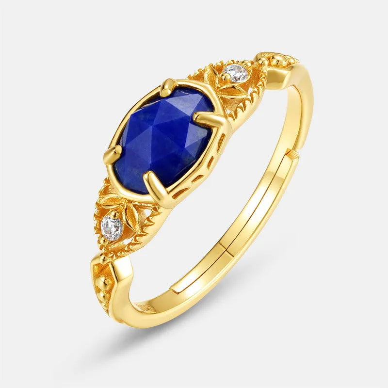 Close-up of a silver alloy ring with an elliptical geometric shape and a central natural lapis lazuli stone.