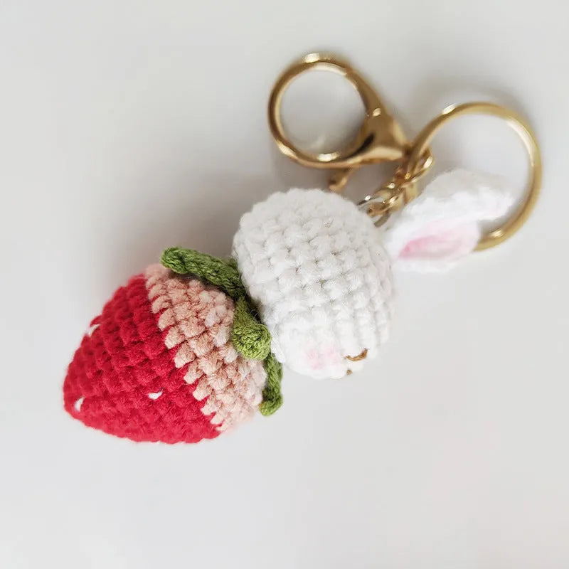 White hand-woven rabbit and strawberry wire pendant with an attached key.
