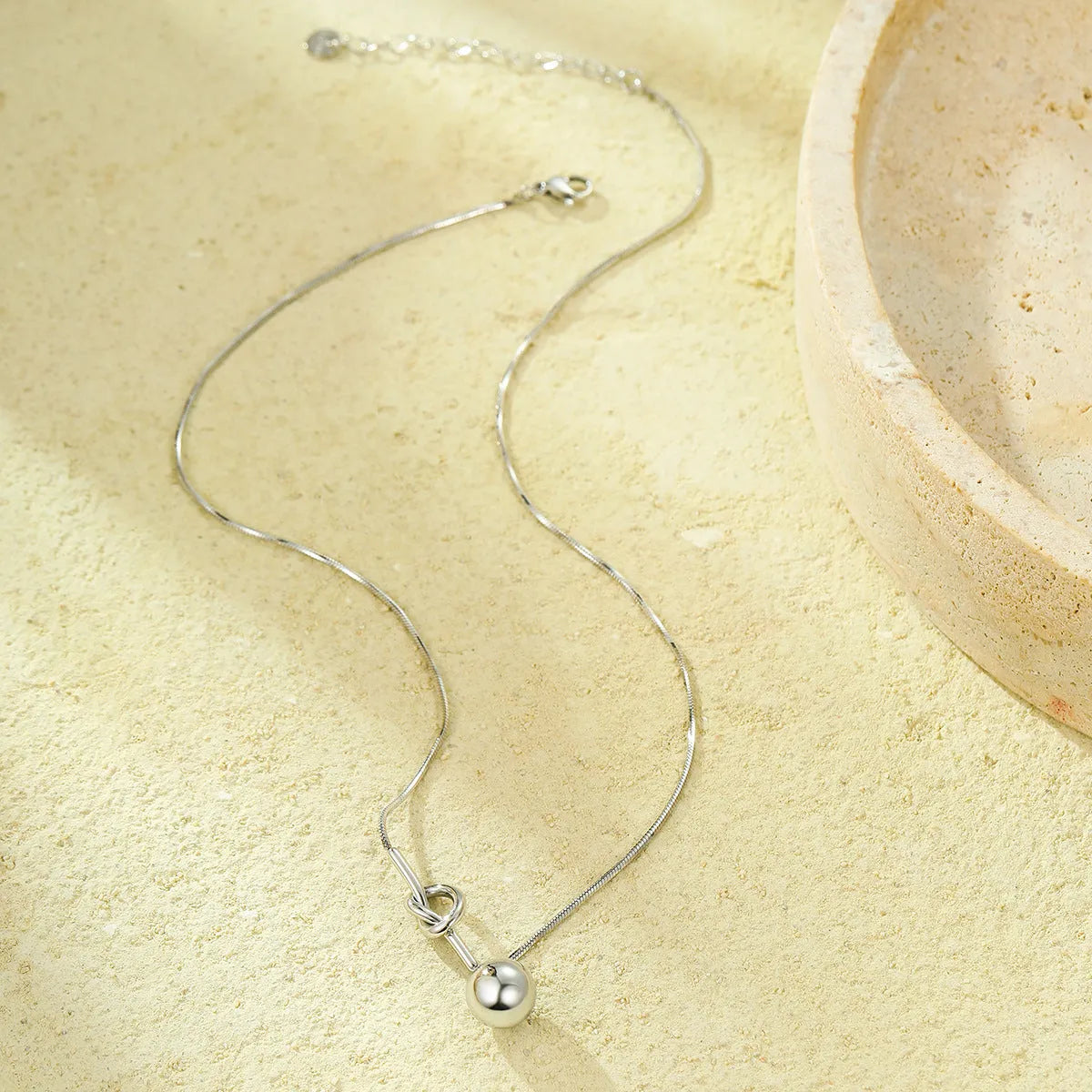 18K gold plated stainless steel winding ball pendant necklace for women on a white background