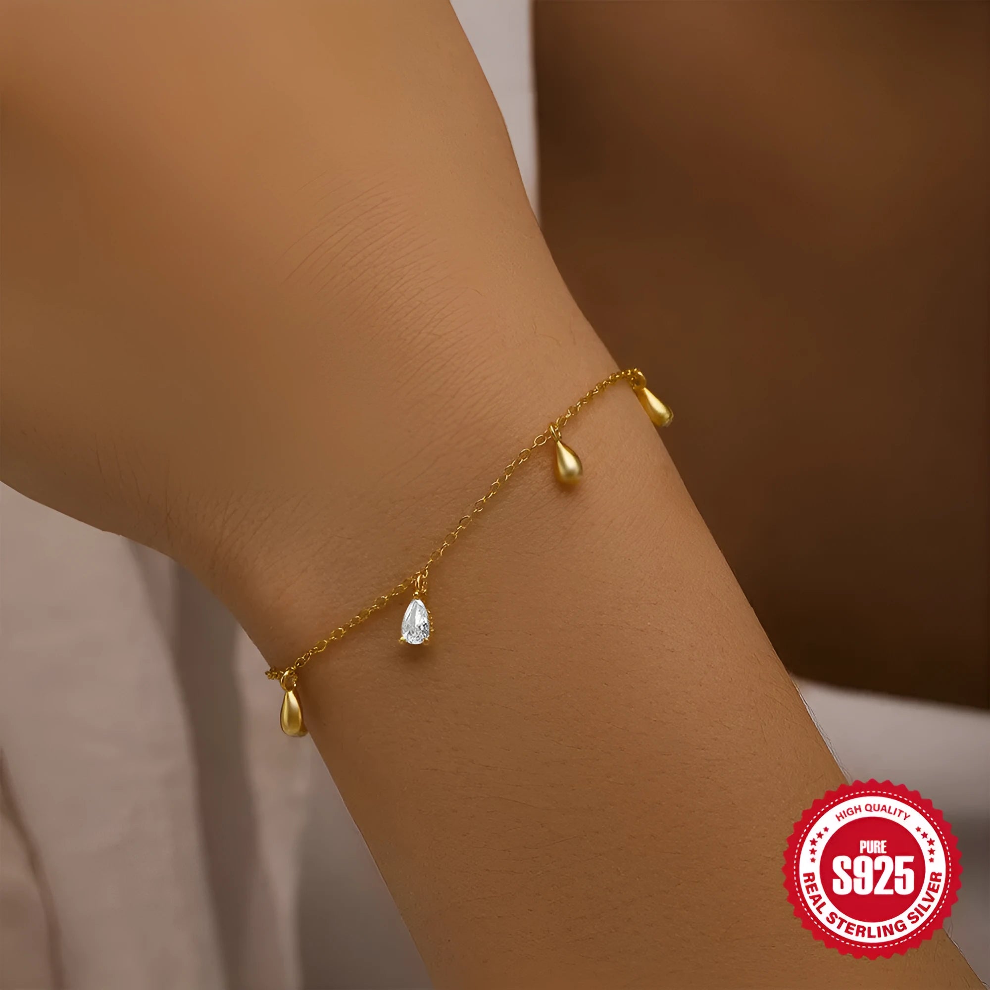 Gold plated sterling silver bracelet with a water droplet shaped diamond pendant on a woman's wrist