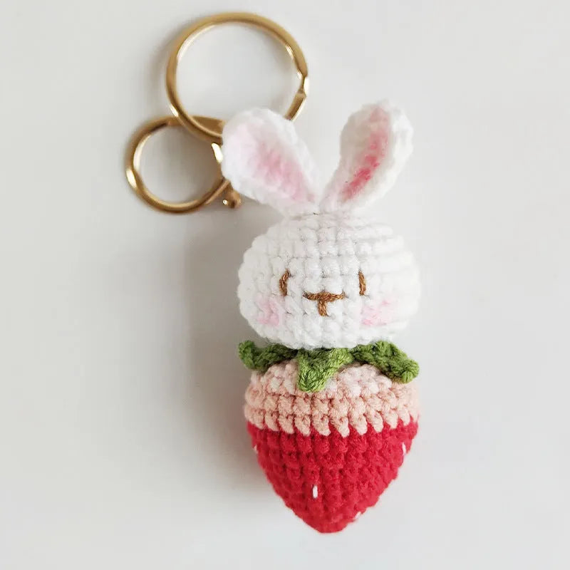 White hand-woven rabbit and strawberry wire pendant with an attached key.