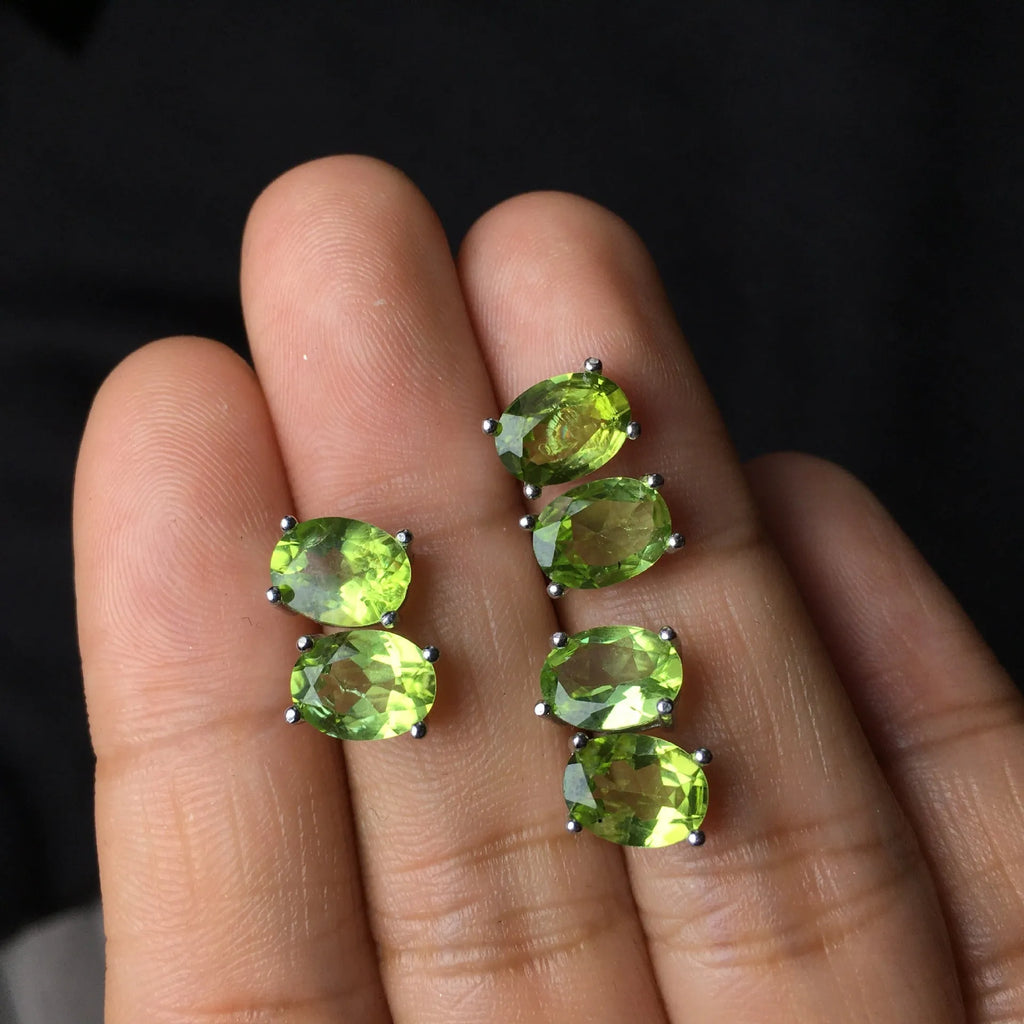 Close-up of grass green olivine stud earrings in sterling silver, showing elliptical faceted stone.