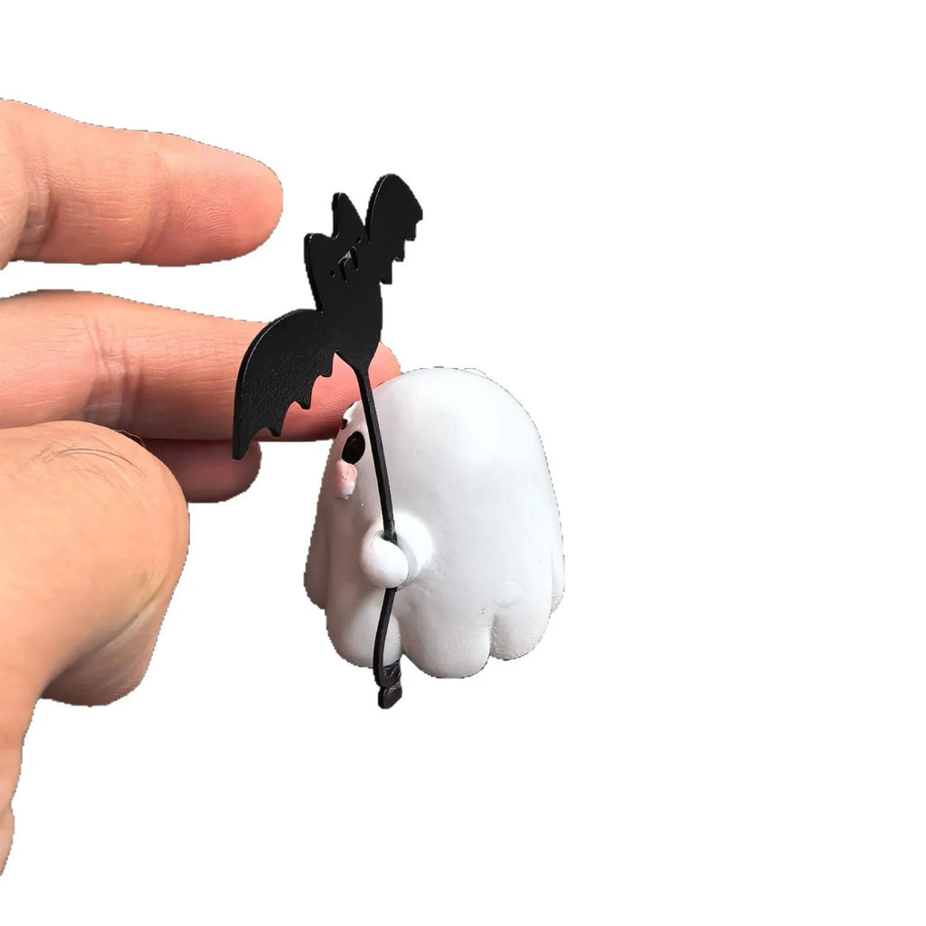 Miniature resin statue of a walking ghost dog holding a bat, a Halloween decoration.