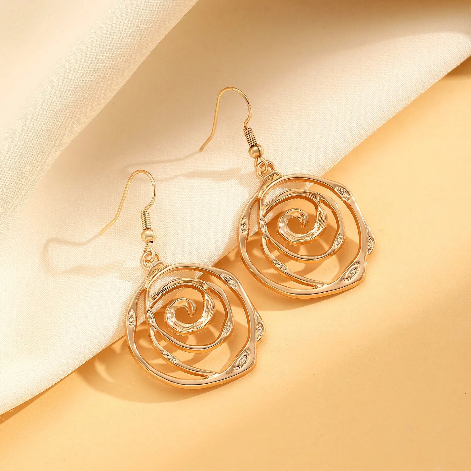 Gold spiral donut charm jewellery set showing necklace, bracelet and earrings on a white background