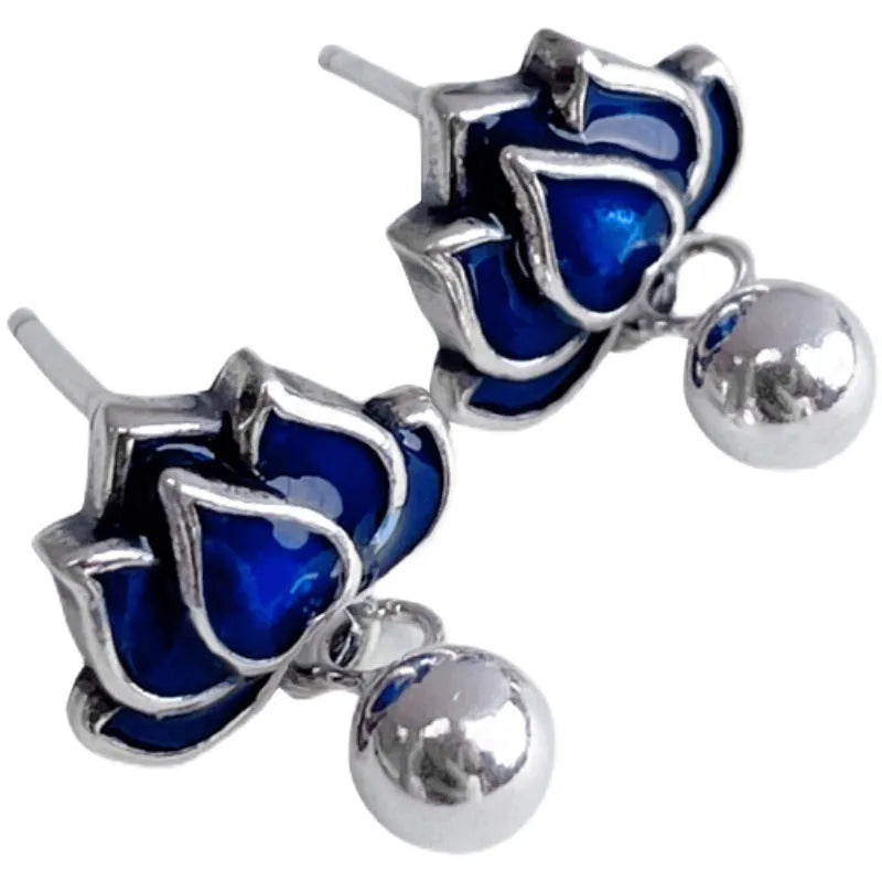Close-up of blue lotus flower stud earrings with a silver tassel drop on an alloy ear post.