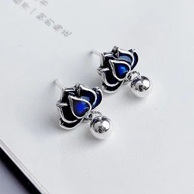 Close-up of blue lotus flower stud earrings with a silver tassel drop on an alloy ear post.