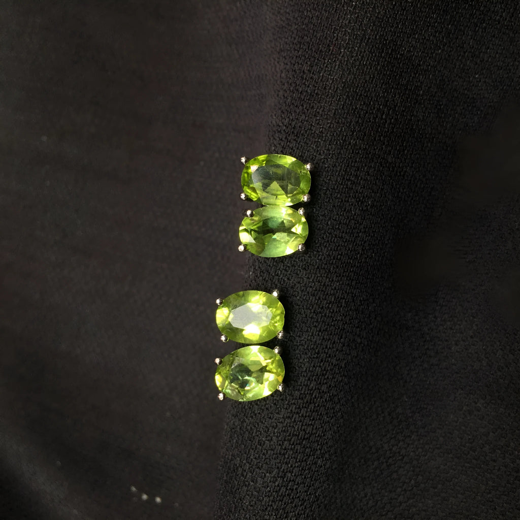 Close-up of grass green olivine stud earrings in sterling silver, showing elliptical faceted stone.