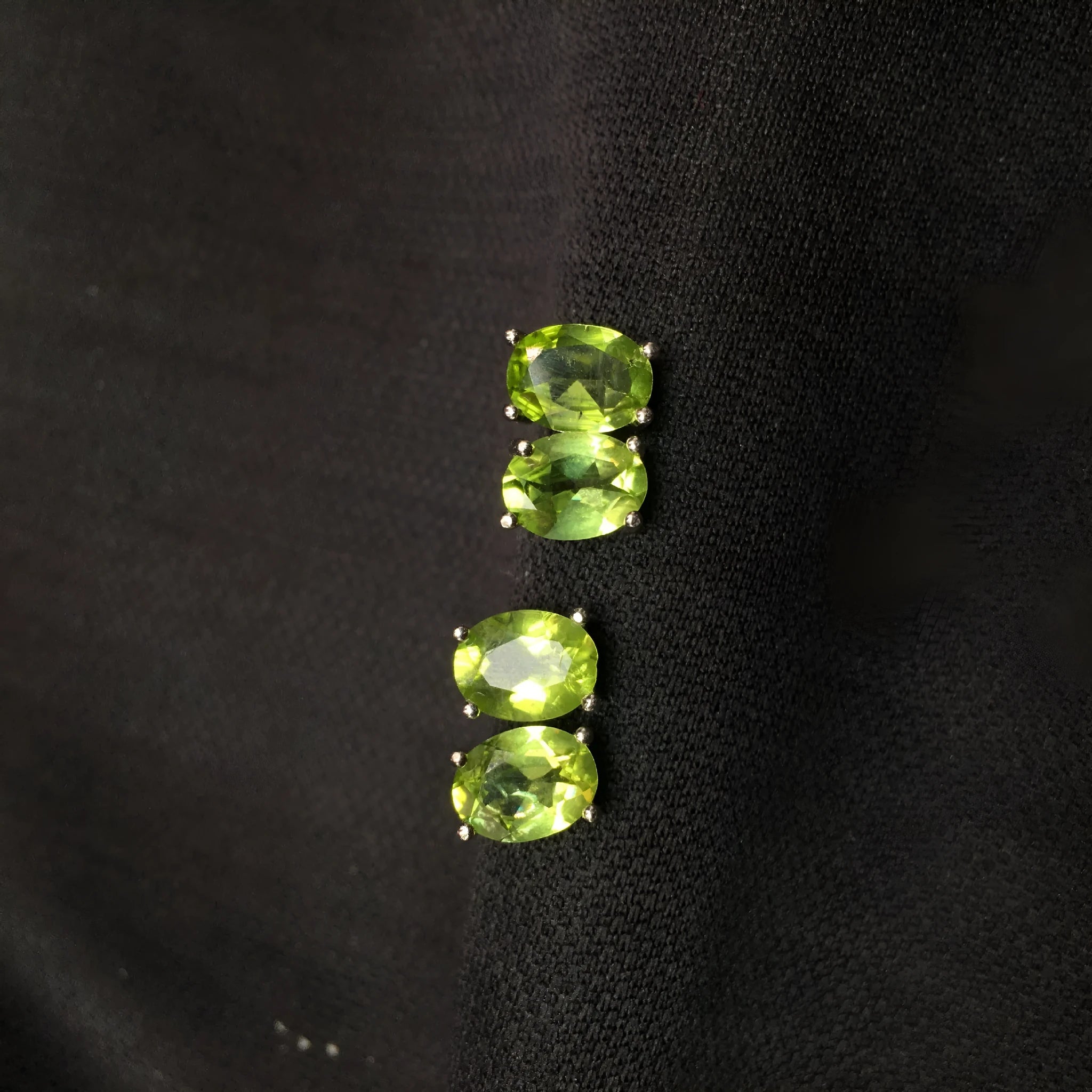 Close-up of grass green olivine stud earrings in sterling silver, showing elliptical faceted stone.