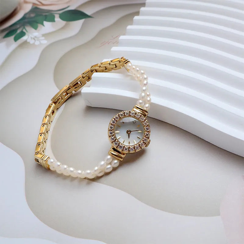 Light gold women's watch with a stainless steel strap featuring integrated freshwater pearls and a round white dial.
