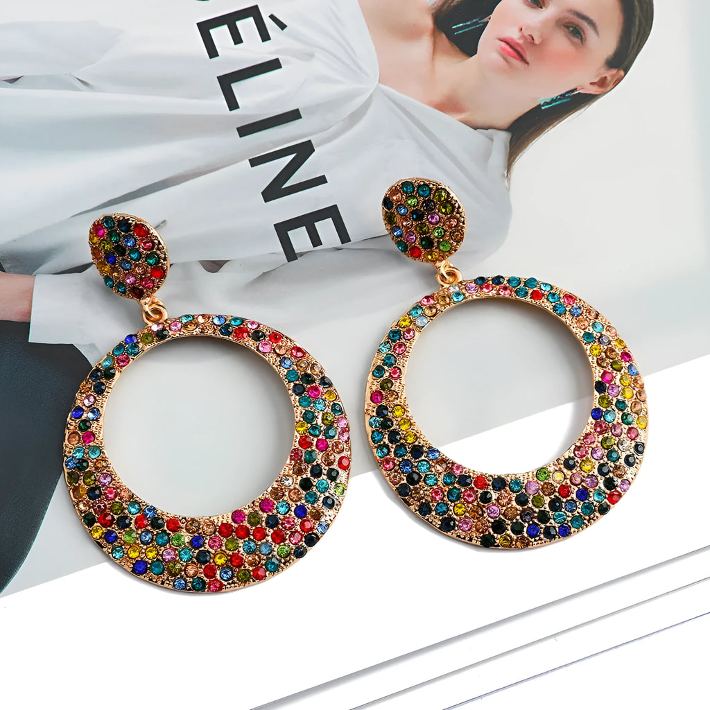 A pair of colourful metal alloy drop earrings with a large round pendant and diamond accents.