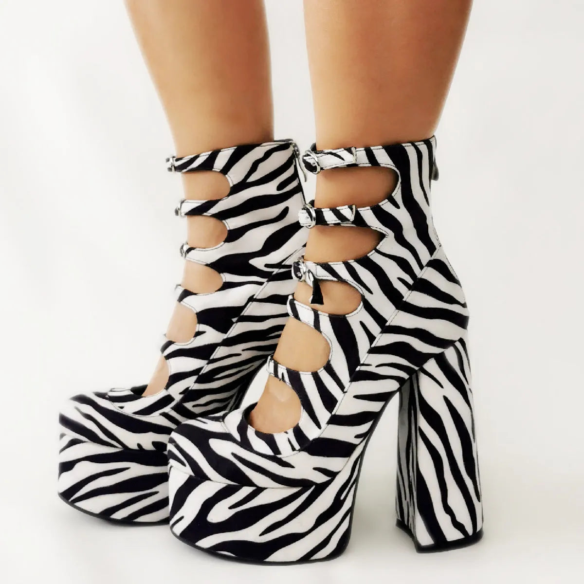 Black women's waterproof patent leather platform ankle boots with a thick heel and serpentine belt buckle fastened.