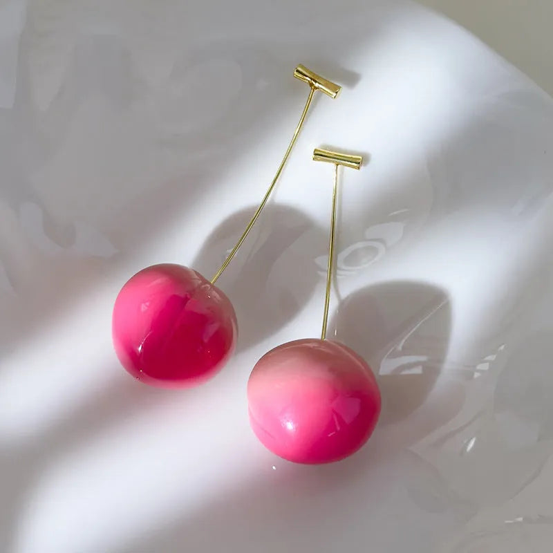 A pair of acrylic peach fruit earrings on a copper post, showing small and large size options.
