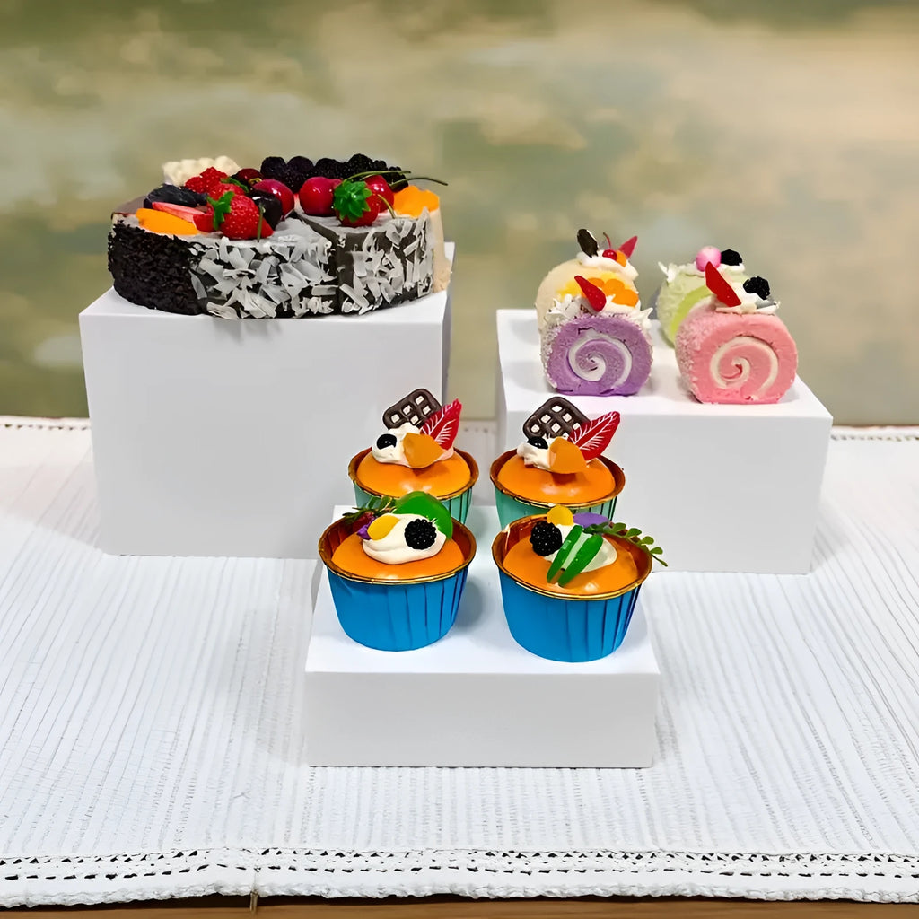 Six white modular plastic cube units arranged as a tiered dessert display stand holding cupcakes.